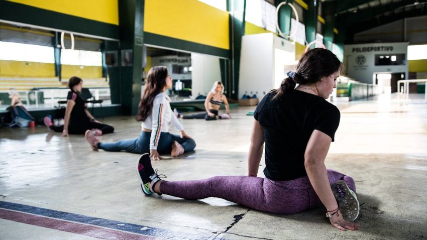 Women engaging in a group stretching session in an indoor gym.